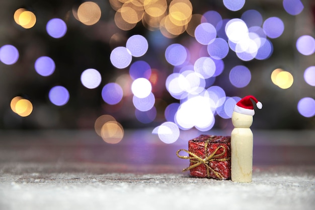 Santa claus with red Christmas gift box on wooden table with bokeh background and copy space Merry Christmasholidaypresent concept