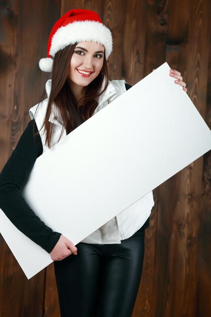 Santa girl holding blank vintage sign billboard Christmas woman in Santa hat showing paper