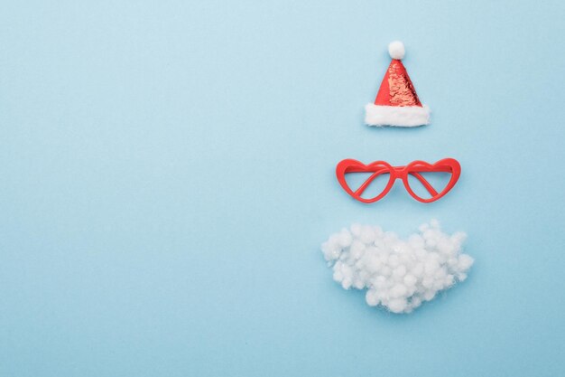 Santa hat beard and glasses on color background top view Flat lay