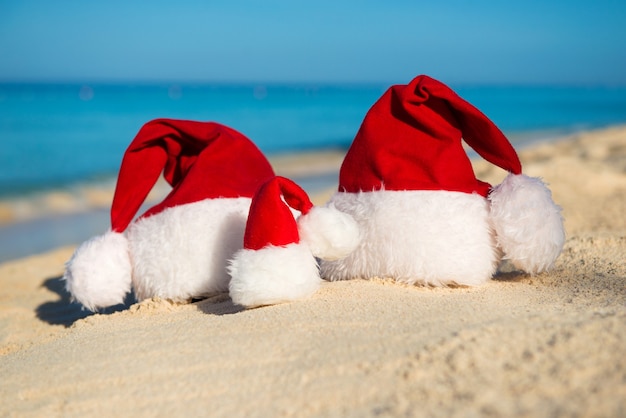 Santa hats on sandy beach  - concept of New Year family holiday with the children on the sea.