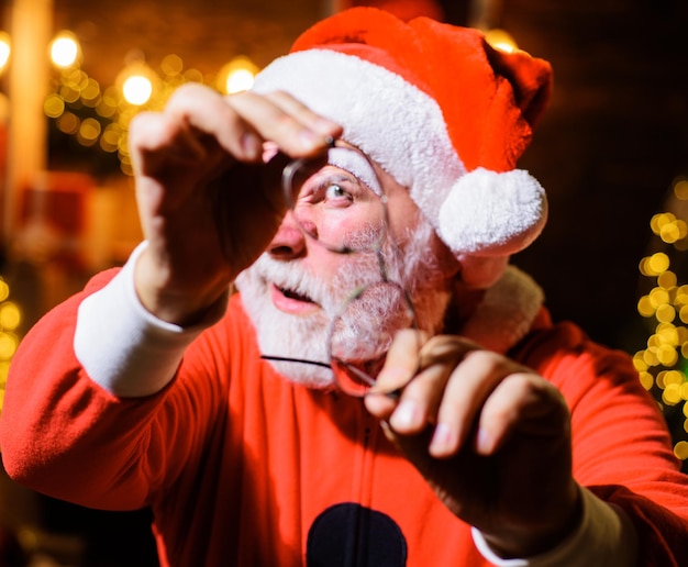 Santa man with broken glasses bearded male in santa costume looking through cracked eyeglasses