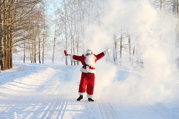 Santa in the winter field. Santa magical fog walking along the field. Santa on Christmas Eve is carrying presents to children in a red bag