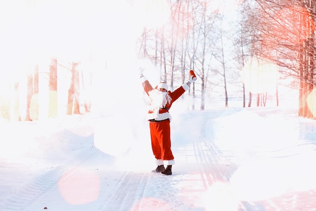 Santa in the winter field. Santa magical fog walking along the field. Santa on Christmas Eve is carrying presents to children in a red bag