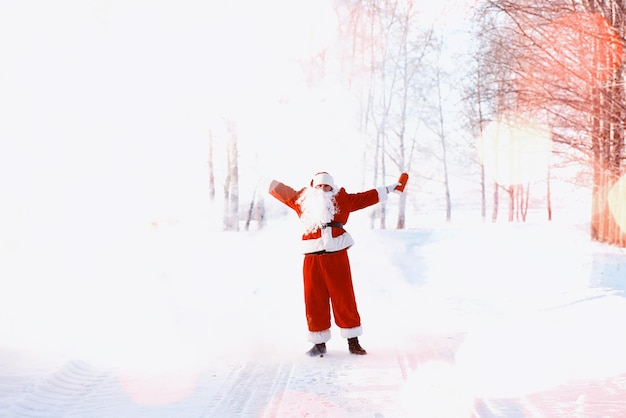 Santa in the winter field. Santa magical fog walking along the field. Santa on Christmas Eve is carrying presents to children in a red bag