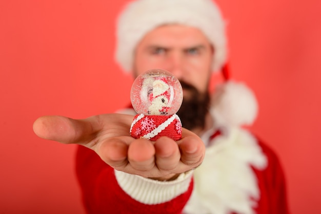 Santa with small christmas snow globe selective focus christmas snowglobe in hand christmas