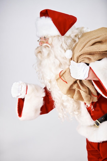 Santas on his way Santa Claus running with a sack of presents on his back isolated on white