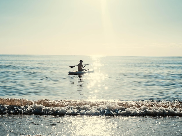 Sap surfer boy on the sea on a clear summer day