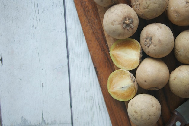 Sapodilla fruit on a chopping board on table