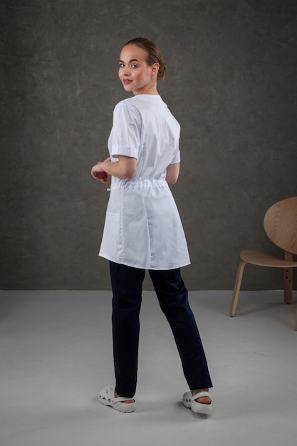 Saratov Russia 7202022 Medical clothes white on the girl model Dress concept for doctor and nurse on a dark gray neutral background