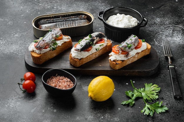 Sardines sandwich with smoked fish set, on black dark stone table background