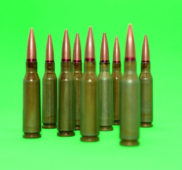 Sartridges for gun weapon with red lines on a bullets with sharpen and soft focus isolated on green