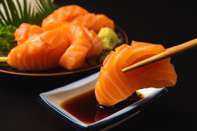 Sashimi Salmon Japanese food chopsticks and wasabi on the black table