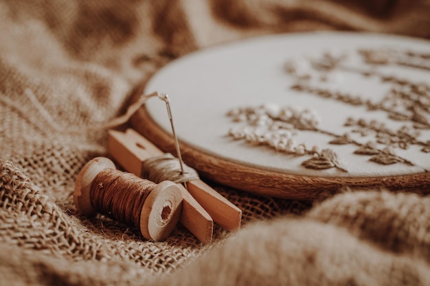 Satin stitch embroidery hoop with white cotton fabric and threads on the background of burlap