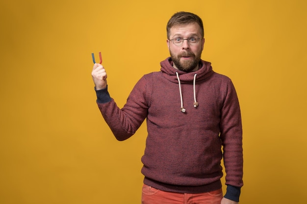 Satisfied attractive man holds a magnet was visited by the idea that he can attract anything