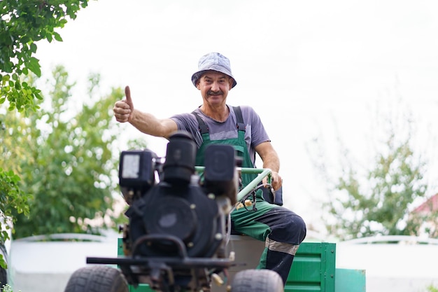 Satisfied farmer portrait sitting behind the wheel of a twowheeled tractor