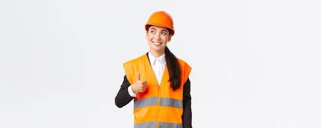 Satisfied happy smiling female asian architect pleased with construction work standing in safety hel