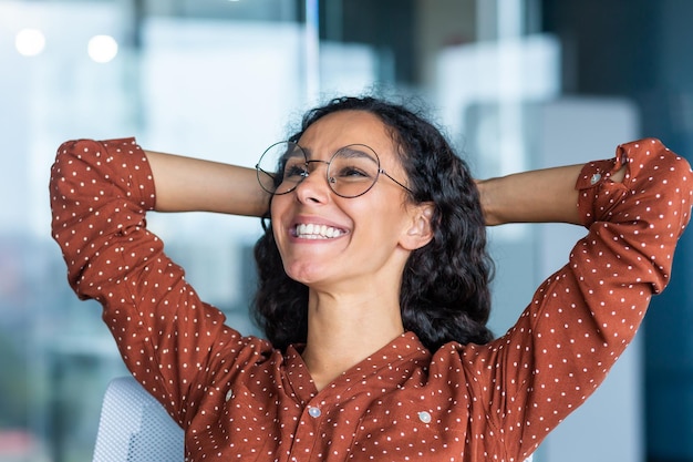 Satisfied happy and successful business woman smiling and resting hispanic female worker finished