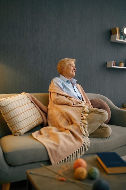 Satisfied old woman wrapped in blanket relaxing