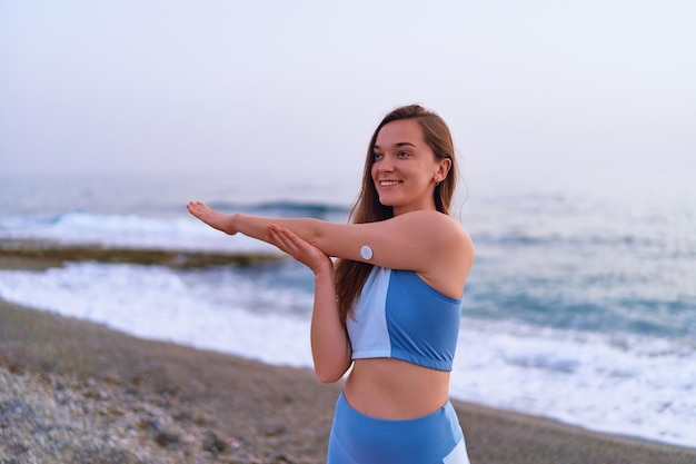 Satisfied one fitness slim diabetic patient woman doing hands stretching exercises by the sea Healthy habits and active sugar diabetes lifestyle