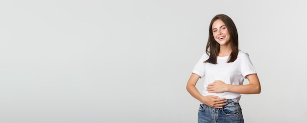 Satisfied smiling brunette girl rubbing belly after eating delicious food