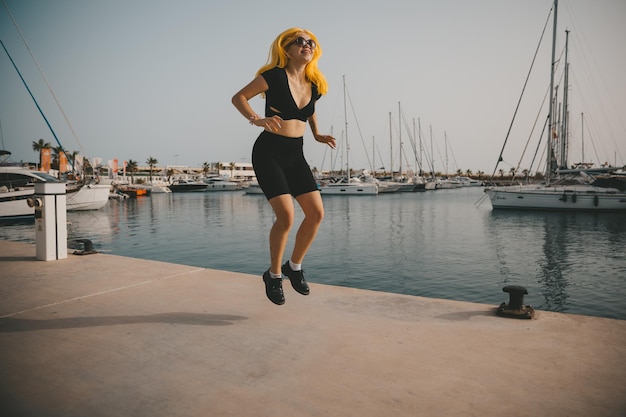 A satisfied woman relaxes by the sea against the background of yachts