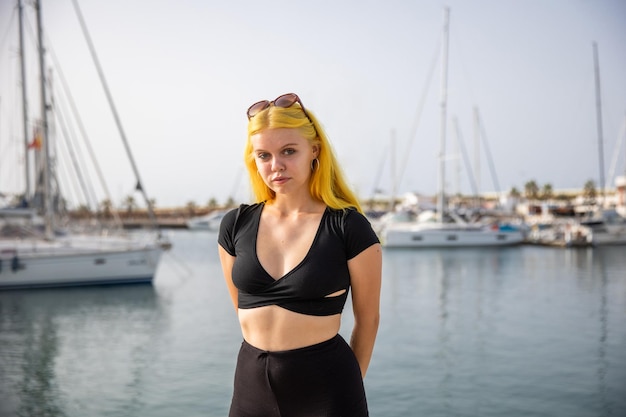 A satisfied woman relaxes by the sea against the background of yachts