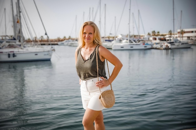 A satisfied woman relaxes by the sea against the background of yachts