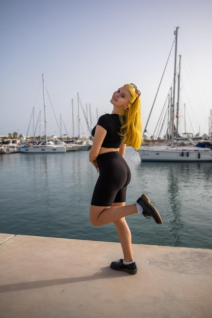 A satisfied woman relaxes by the sea against the background of yachts