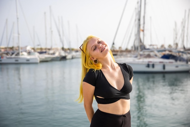 A satisfied woman relaxes by the sea against the background of yachts