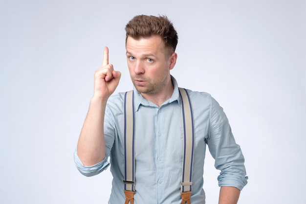 Satisfied young man showing index fingers up giving advice or recommendation