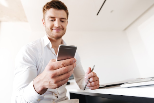 Satisfied young man using mobile phone