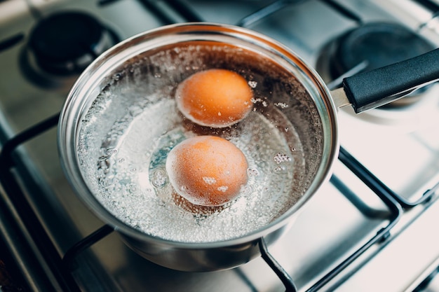 Photo saucepan stainless steel with boiling eggs breakfast in a water on a gas stove