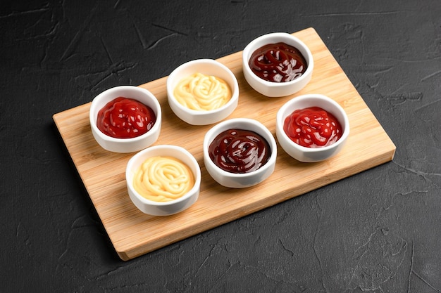 Sauces different sauces on a wooden board on a black background