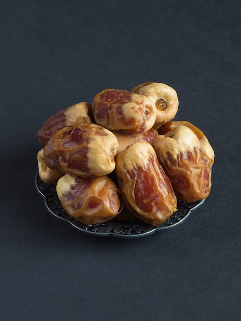 Saudi dates Sagai are laid out on a black table.