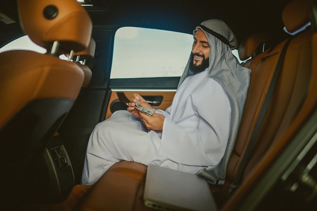 Saudi man in a traditional clothing in a car holding money