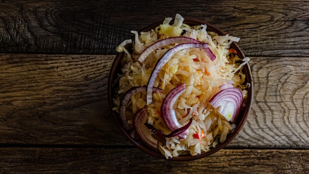 Sauerkraut in earthenware on a wooden background. Cooking homemade fermented food.