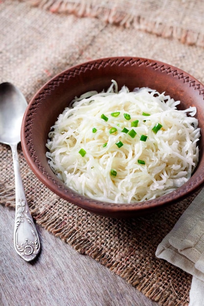 Sauerkraut with green onions in rustic bowl