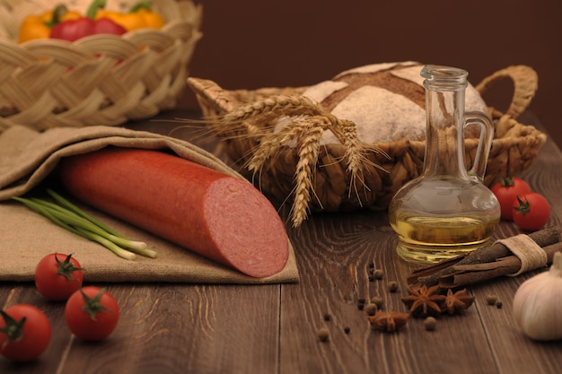 Sausage and bread in a wicker basket and vegetables and garlic on a table