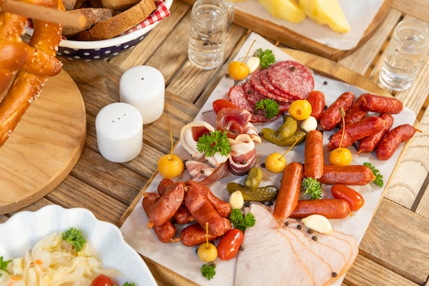 Sausage with cheese and fermented cucumbers, snacks with vodka on the table