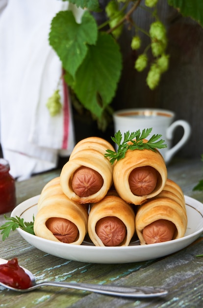 Photo sausages in the dough with sauce on a plate