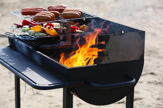 Sausages and vegetables on barbecue grill outdoors