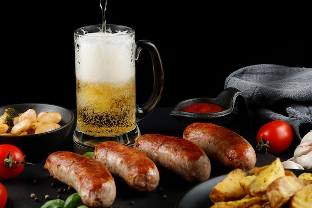 Sausages with beer Fried anchovies and delicious food with beer Grilled sausages with glass of beer on wooden table