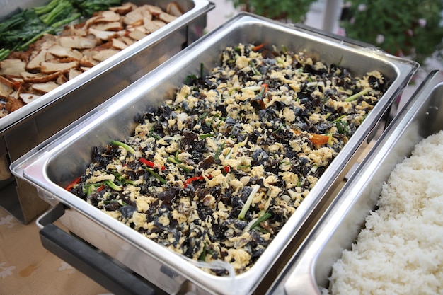 Sauteed Ear Mushroom with Egg in buffet line. The container is a rectangular stainless steel tray. Selective focus.