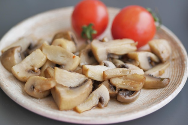 Sauteed mushrooms with garlic and parsley on a black plate on white background