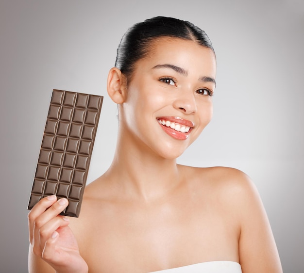 Save the earth its the only planet with chocolate Studio shot of an attractive young woman eating a slab of chocolate against a grey background