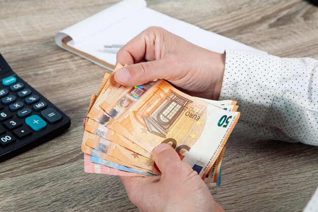 Saving finance economy and housing concept close up of man with calculator counting money and making notes at home