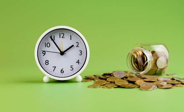 Saving gold coins in glass jars on green background coin savings concept