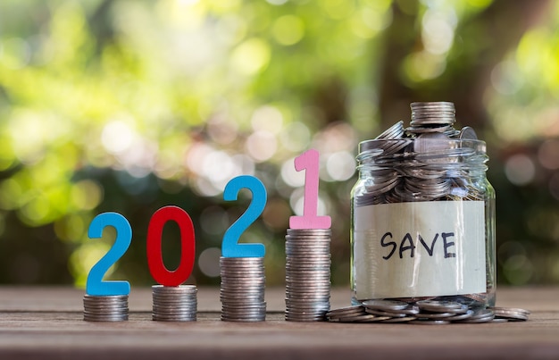 Saving money and coins in a glass bottle on a wooden floor. Investment concept for the future. With bokeh background