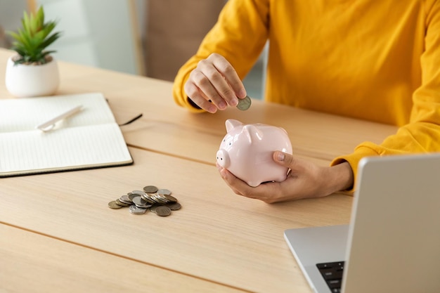 Saving money investment for future female woman hands holding pink piggy bank and putting money coin