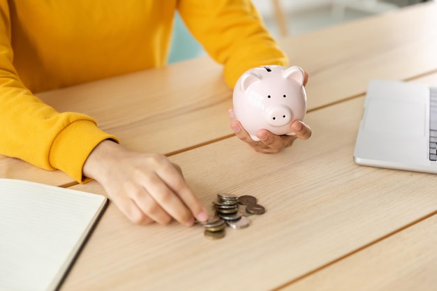 Saving money investment for future female woman hands holding pink piggy bank and putting money coin